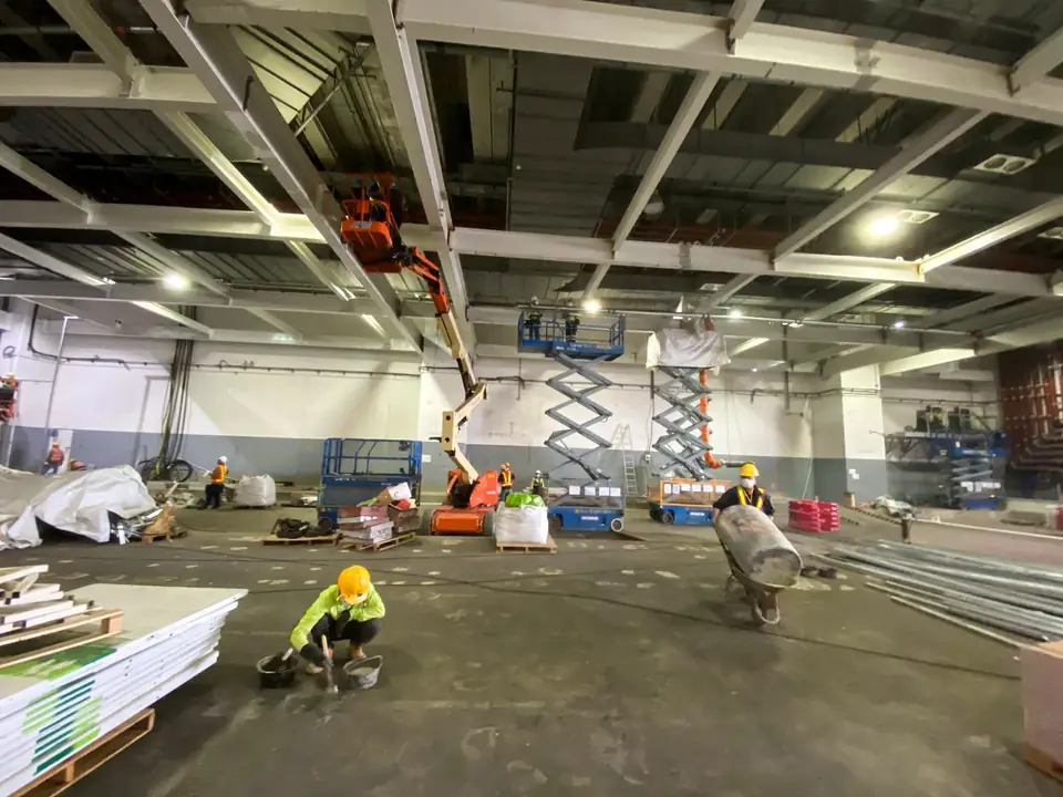 國泰貨運中心大型樓內工程區，多名工人與升降工作台在鋼樑下作業