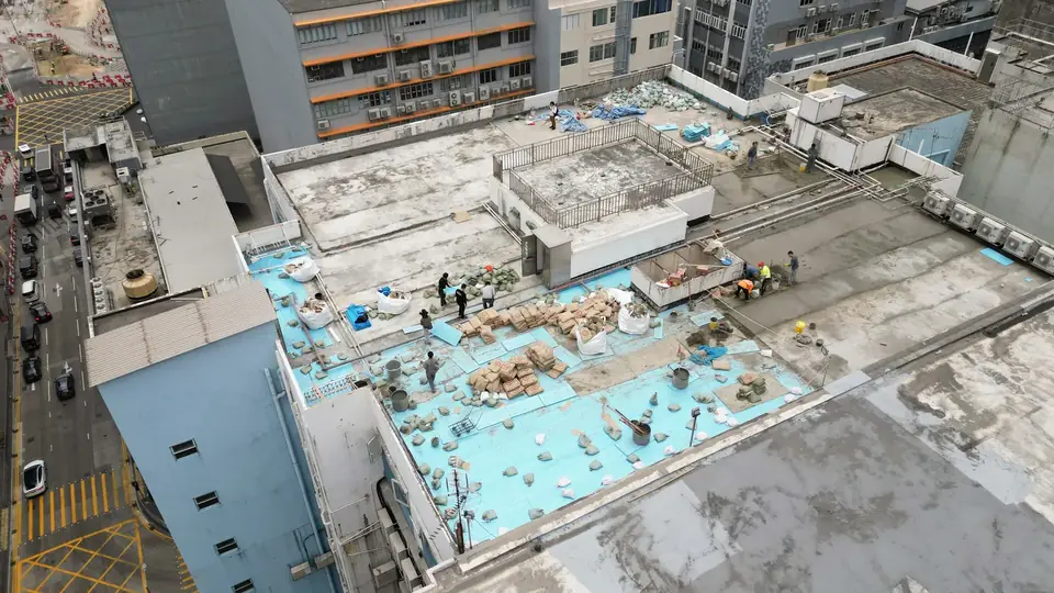 觀塘鴻運工業大廈工程:外露藍色底層、拆除物料及工人的天台航拍