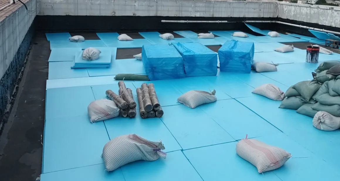 薄扶林道碧瑤灣工程:以沙包、施工管線及磚塊壓穩藍色板材的天台近景