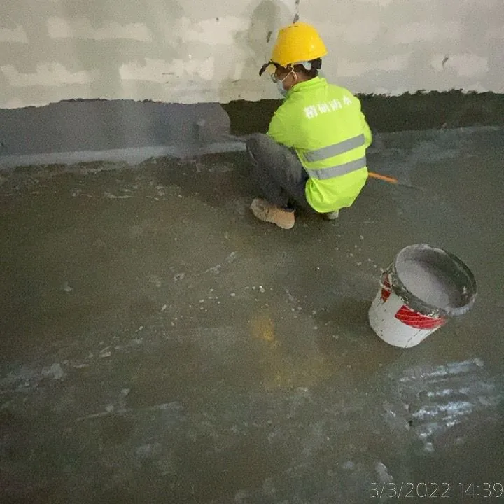 國泰貨運中心工人蹲在牆地接縫旁處理深色牆腳帶,旁邊放有水桶