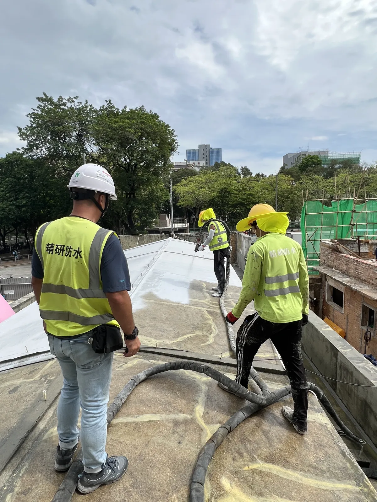 粉嶺聯和市場古蹟屋面上三名工人以輸料管處理分格表面