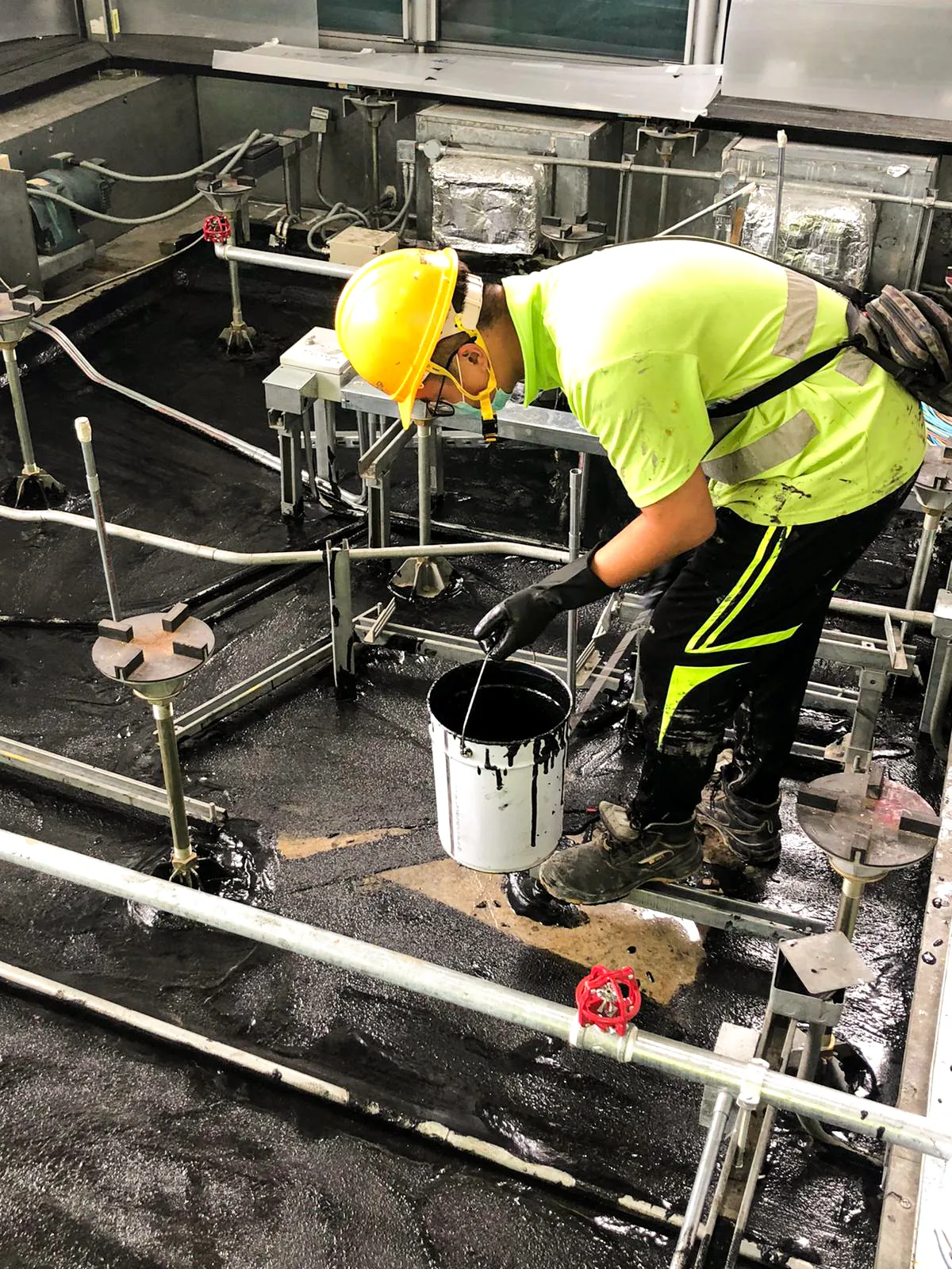 中環匯豐銀行總行內,工人在管道及設備之間以手工具處理深色地面