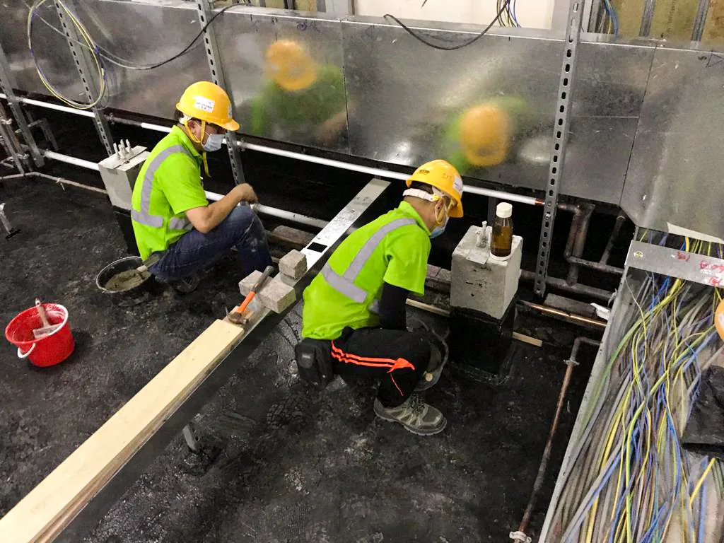 中環匯豐銀行總行內,兩名工人在設備及電纜束旁跪地施工