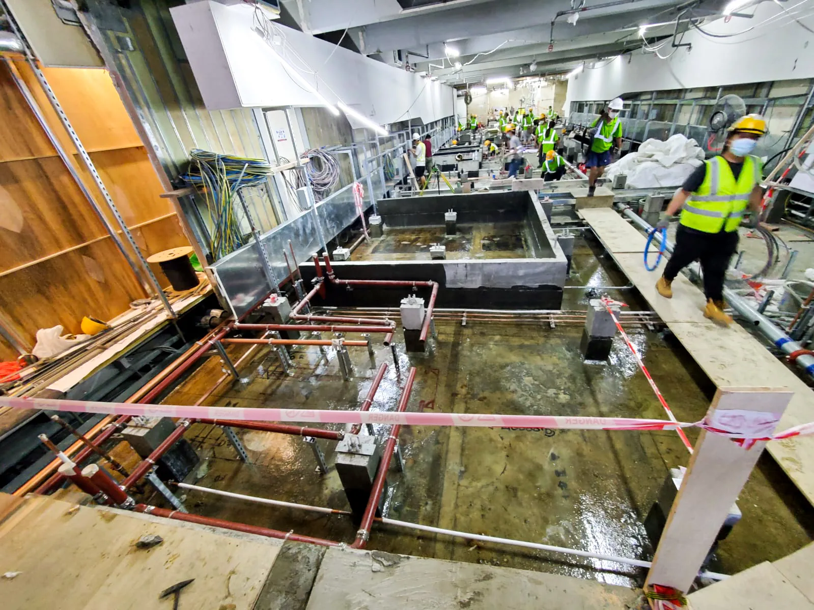 中環匯豐銀行總行樓內工程區全景,可見管道、圍欄及地面施工人員