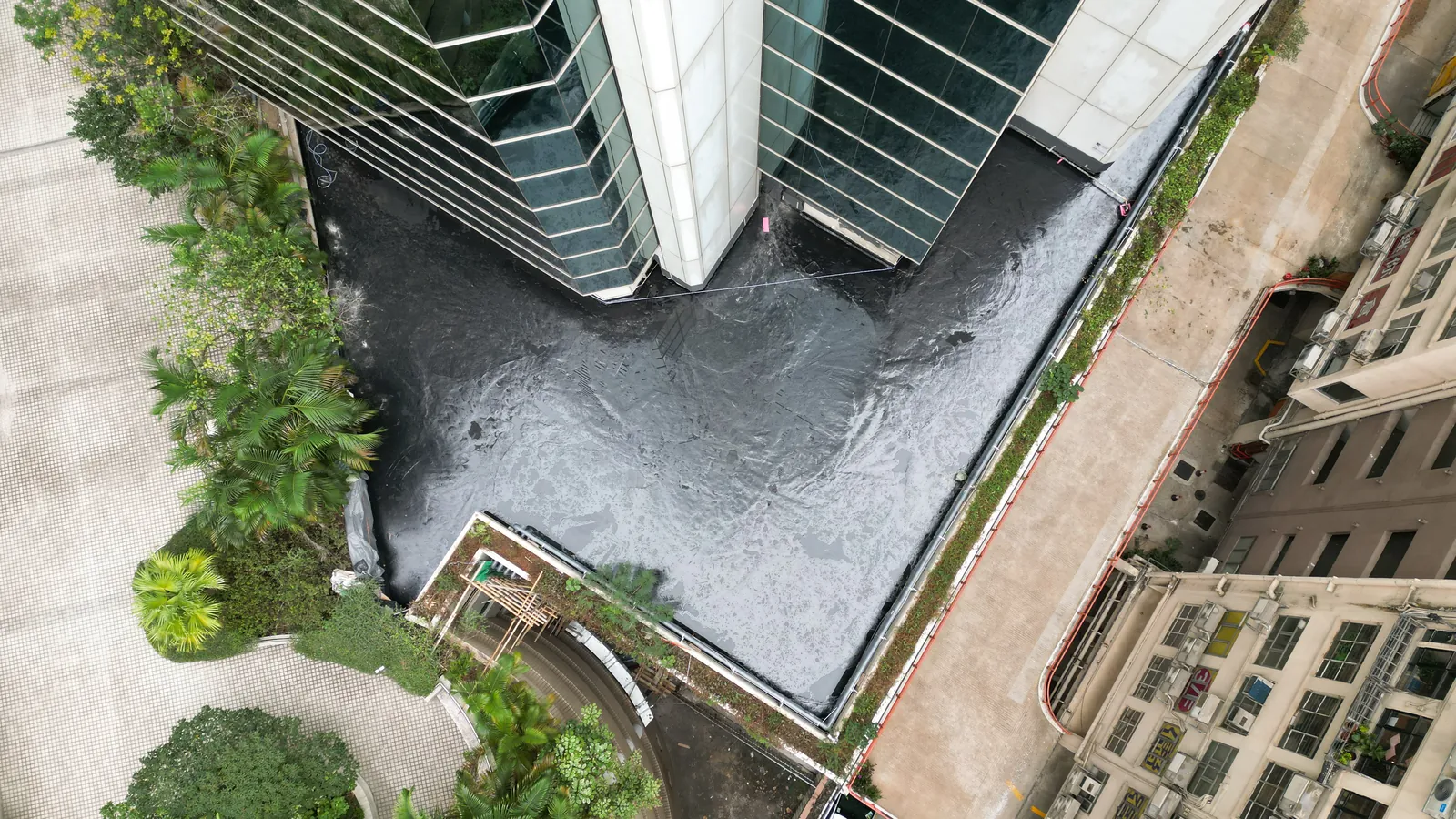 高處俯瞰炮台山理文商業中心玻璃大樓旁的深色平台表面與周邊綠化