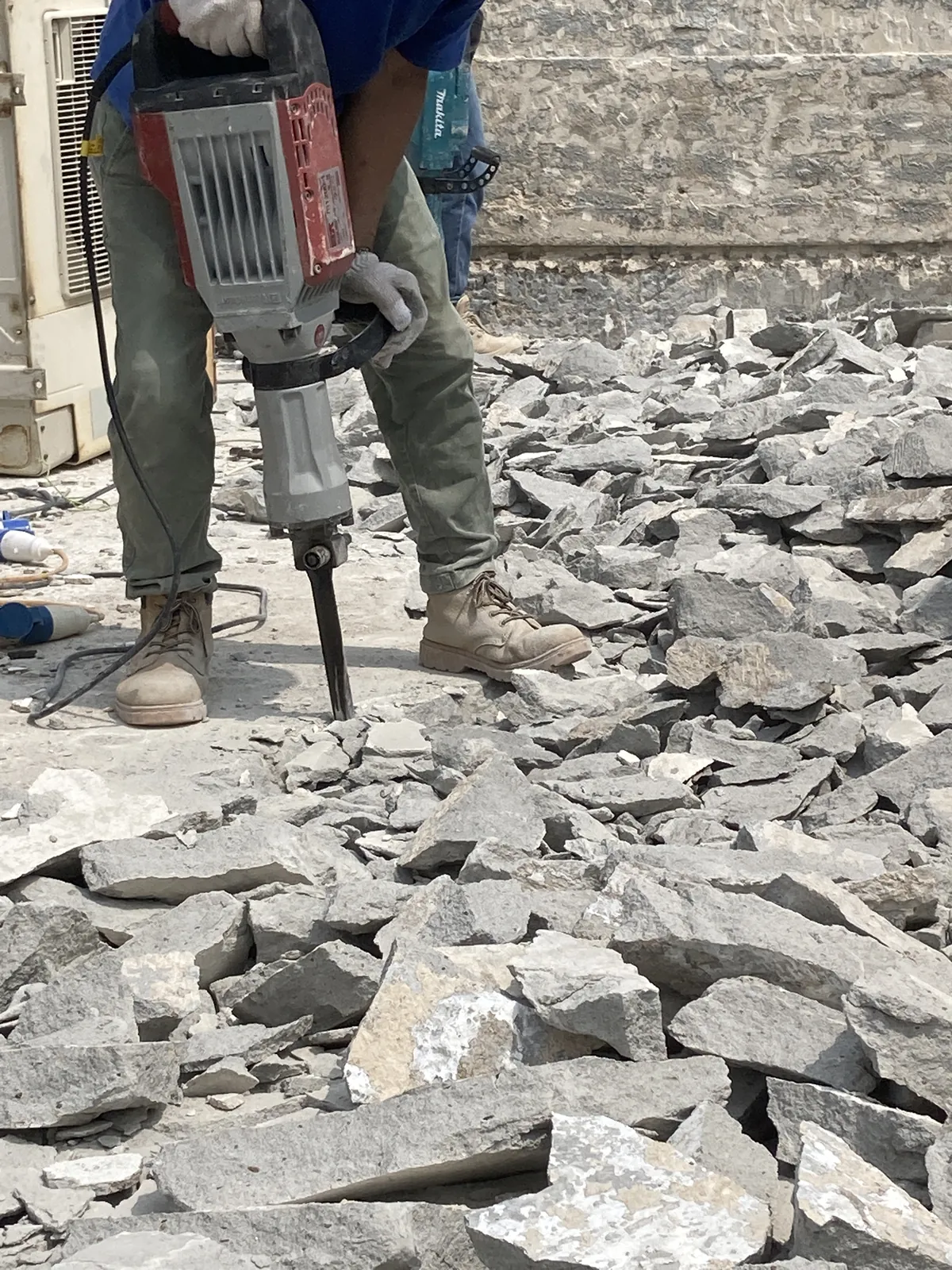 西貢灣景街工人使用電動破碎錘打鑿天台地面，周圍堆有碎塊