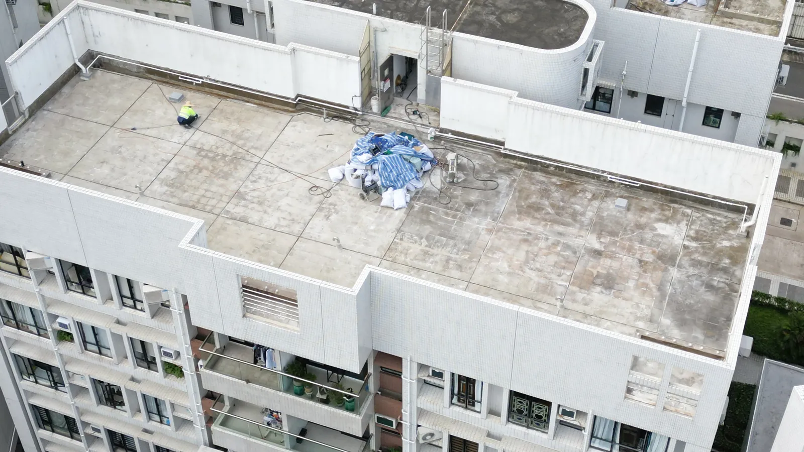 高處俯瞰華翠園住宅天台,斑駁屋面上可見一名工人及覆蓋物料